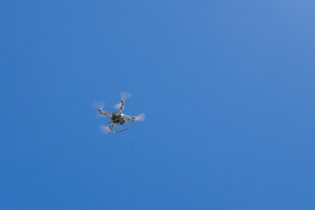 Drone Quadcopter con la cámara flotando en el cielo azul