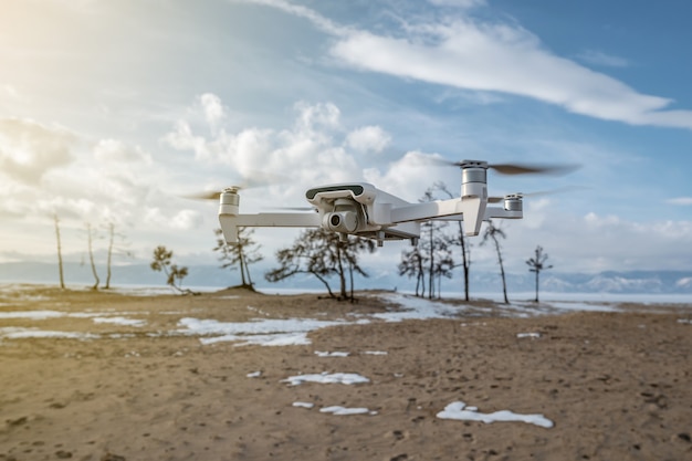 Drone quadrocopter blanco con cámara cuelga en el aire en el fondo de la hermosa naturaleza en invierno