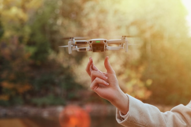 Drone quadrocopter decolando das mãos do homem ao ar livre. Jovem, liberando o helicóptero aéreo para voar com uma pequena câmera digital voadora. Conceito de tecnologia moderna em nossa vida. Copie o espaço para o site