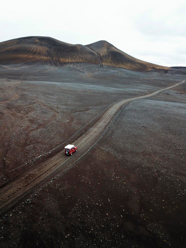 Drone vista de un Suzuki Jimny conduciendo por un camino de tierra