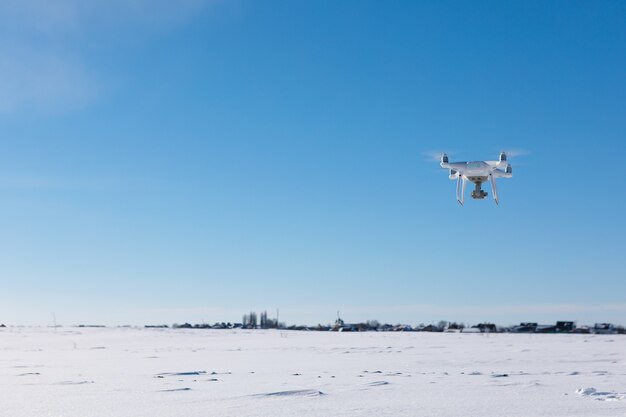 Drone voando acima do campo coberto de neve em um dia ensolarado de inverno