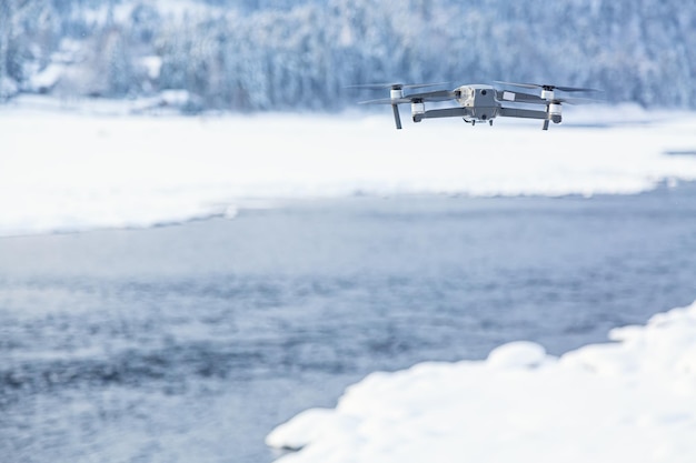 Drone volador contra el fondo de invierno con río y bosque.