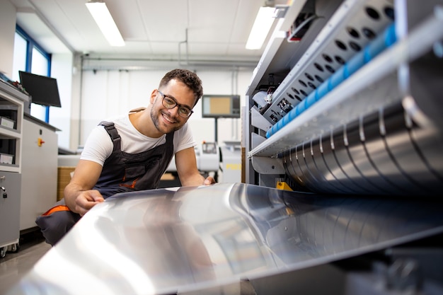 Foto druckarbeiter, der am computer arbeitet, um maschine in der druckerei zu platten.