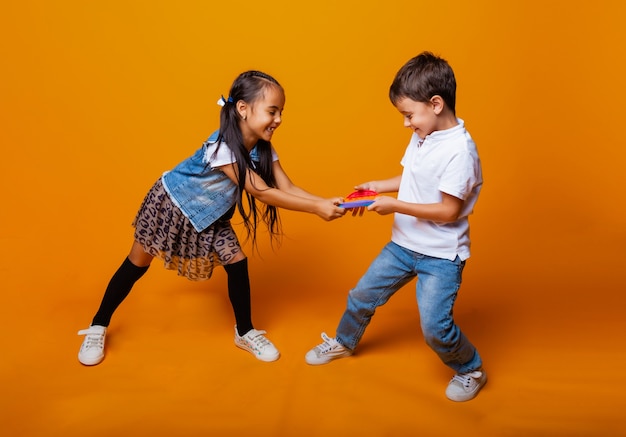 Druckknopf-Silikonspielzeug Antistress. Kinder spielen mit Pop it auf gelbem Hintergrund.