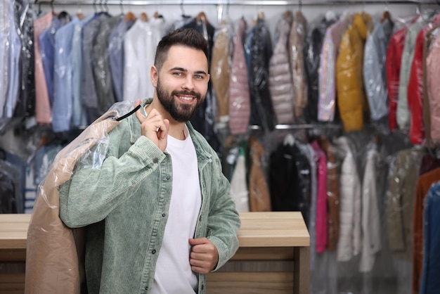 Drycleaning-Service Glücklicher Mann mit Hänger mit Mantel in Plastiktüte Innenraum für Text