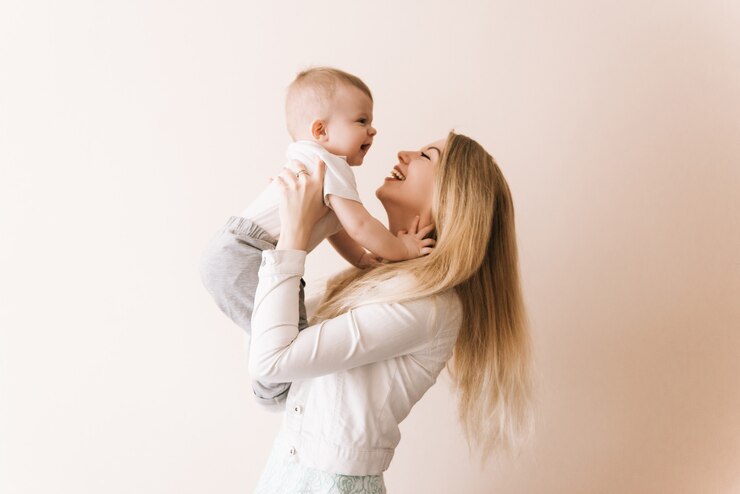 Du bist mein Schatz! fröhliche schöne junge Frau, die Baby in ihren Händen hält und ihn mit Liebe zu Hause ansieht