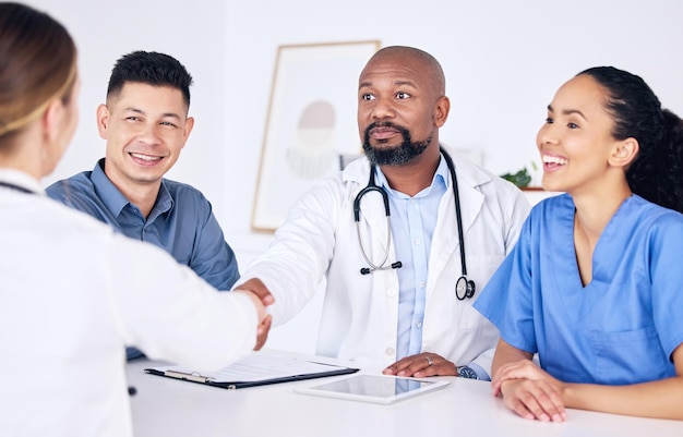 Du bist offiziell Teil des Teams. Aufnahme von zwei Ärzten, die sich in einer Klinik die Hand geben.