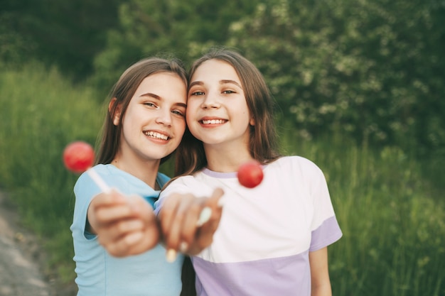 Duas adolescentes felizes segurando um doce pirulito vermelho brilhante