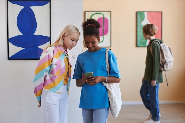 Duas adolescentes ouvindo guia online na galeria de arte