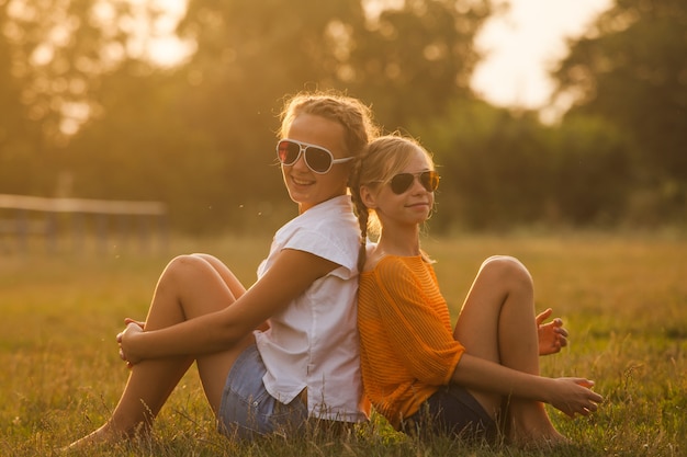 Duas adolescentes se divertem no parque. Dois amigos ao ar livre. Verão pessoas de óculos