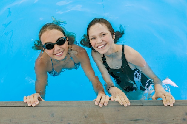 Foto duas adolescentes se divertindo na piscina.