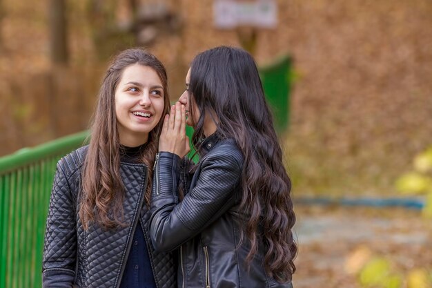 Duas adolescentes sorrindo de pé ao ar livre