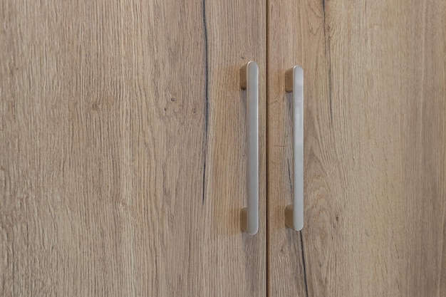 Duas alças na porta de um armário de madeira de cor clara