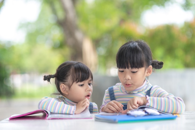 Duas aluna garotas asiáticas lendo o livro sobre a mesa