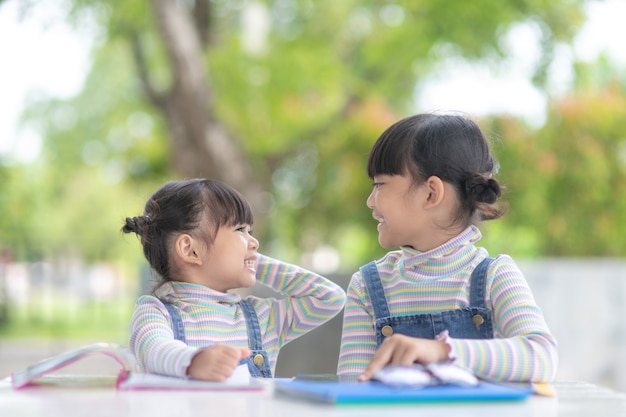 Duas aluna garotas asiáticas lendo o livro sobre a mesa