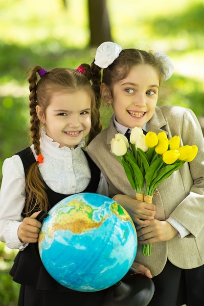 Duas alunas alegres com flores e um globo