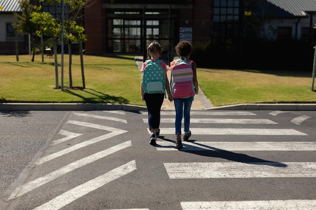 Foto duas alunas atravessando a rua em uma passagem para pedestres
