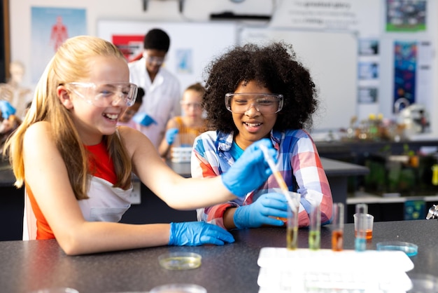 Foto duas alunas felizes e diversas fazendo uma experiência na aula de química.