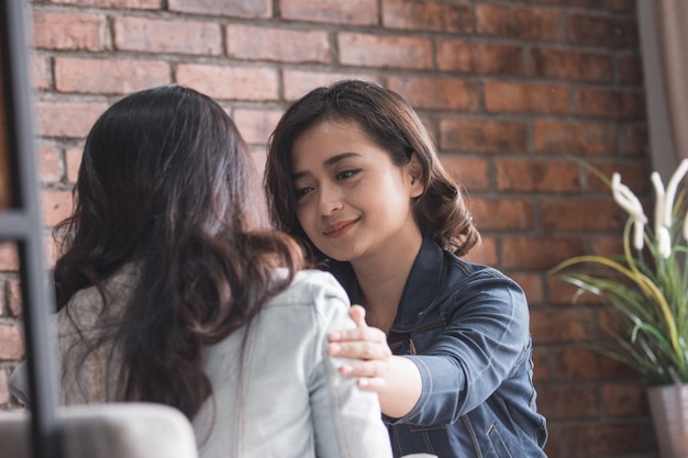 Duas amigas a abraçam