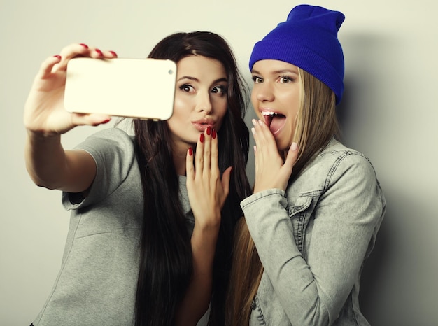 Duas amigas adolescentes vestidas de hipster fazem selfie