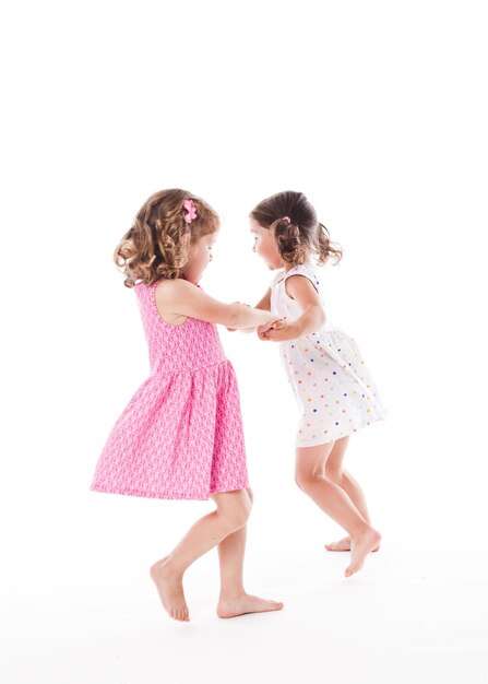 Duas amigas adoráveis dançando isoladas no branco