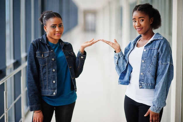 Duas amigas africanas em jaqueta jeans mostram as mãos juntas no interior