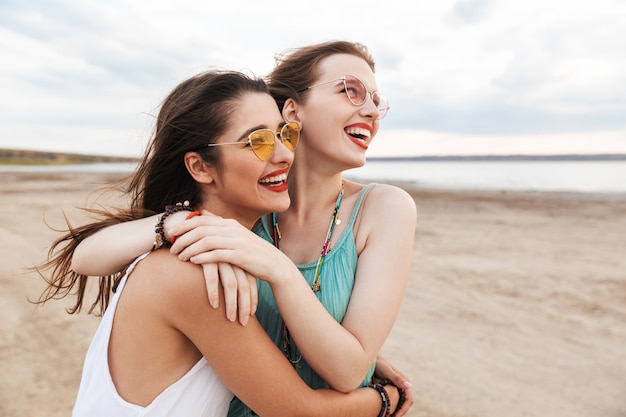 Duas amigas alegres passando um bom tempo na praia, rindo