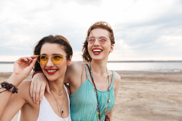 Foto duas amigas alegres passando um bom tempo na praia, rindo