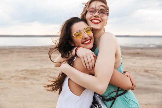 Duas amigas alegres passando um bom tempo na praia, rindo