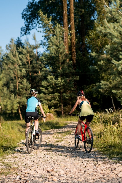 Duas amigas andando de bicicleta offroad na floresta