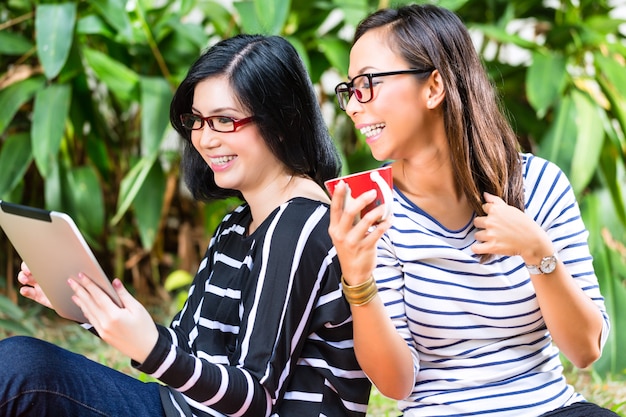 Duas amigas asiáticas com computador tablet