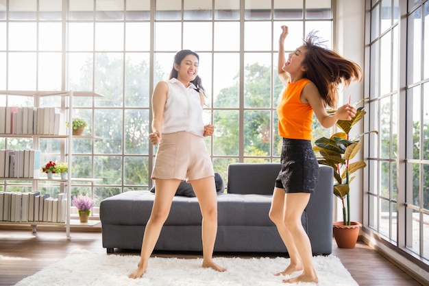 Duas amigas asiáticas dançando na sala de casa