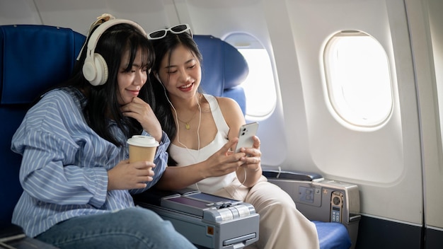 Duas amigas asiáticas felizes estão gostando de conversar durante o voo para suas férias juntas
