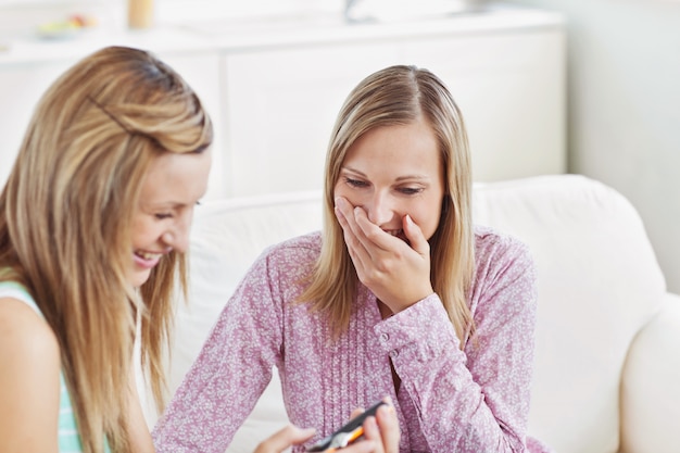 Duas amigas bonitas usando uma câmera digital em um sofá