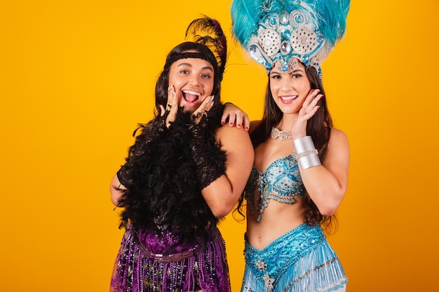 Duas amigas brasileiras com roupas de rainha do carnaval da escola de samba Coroa de penas posando para foto