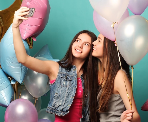 Duas amigas com balões coloridos fazem selfie em um ph