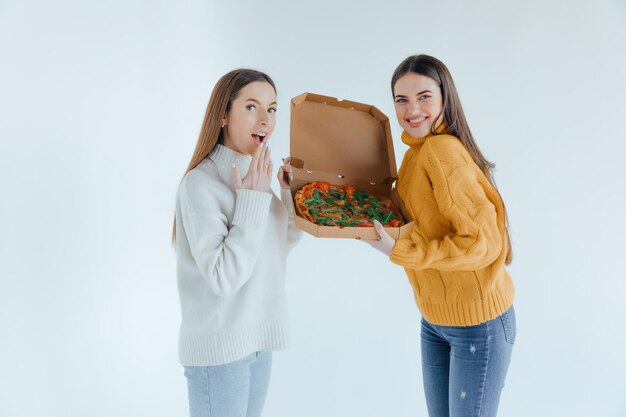 Duas amigas comendo pizza.