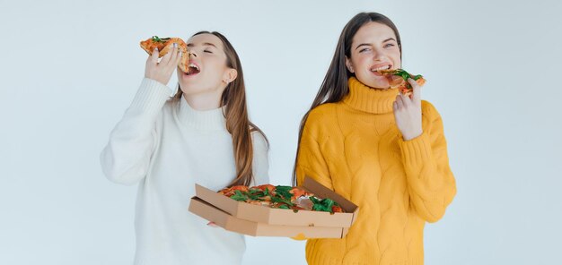 Duas amigas comendo pizza.