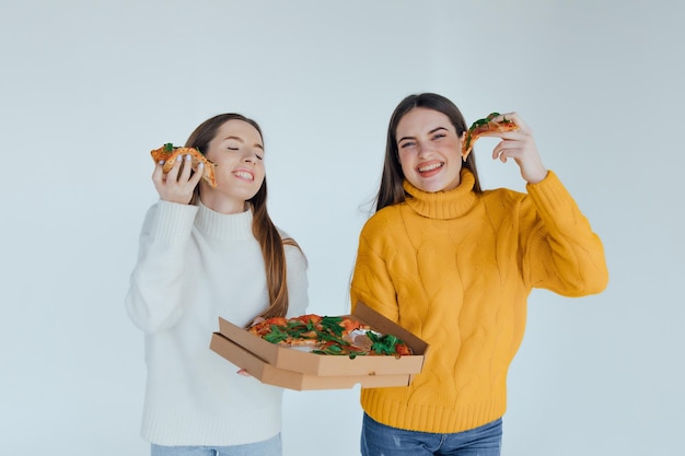 Duas amigas comendo pizza.