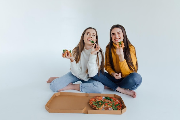 Duas amigas comendo pizza.