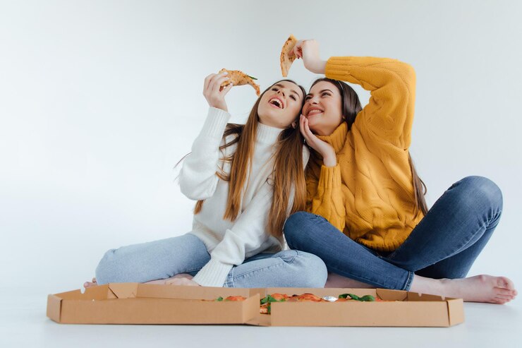 Duas amigas comendo pizza.
