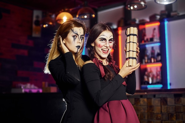 Duas amigas estão na festa de halloween temática com maquiagem assustadora e fantasias com bomba-relógio.