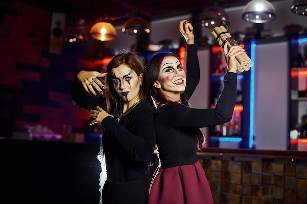 Duas amigas estão na festa de halloween temática com maquiagem assustadora e fantasias com bomba-relógio.