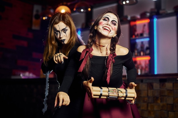 Duas amigas estão na festa de halloween temática com maquiagem assustadora e fantasias com bomba-relógio.