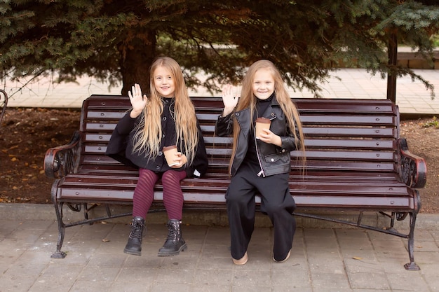 duas amigas estão sentadas em um banco de parque com chocolate nas mãos, conversando docemente