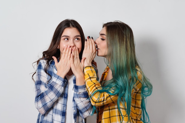 Foto duas amigas fofocando. uma garota conta os segredos da outra no ouvido