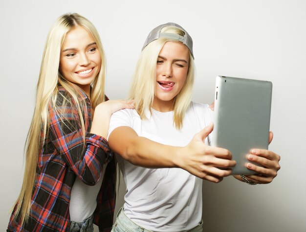 Duas amigas hippie tirando selfie com tablet digital cinza