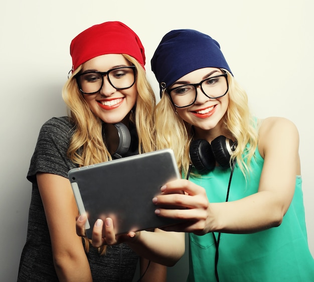 Duas amigas hippie tirando selfie com tablet digital