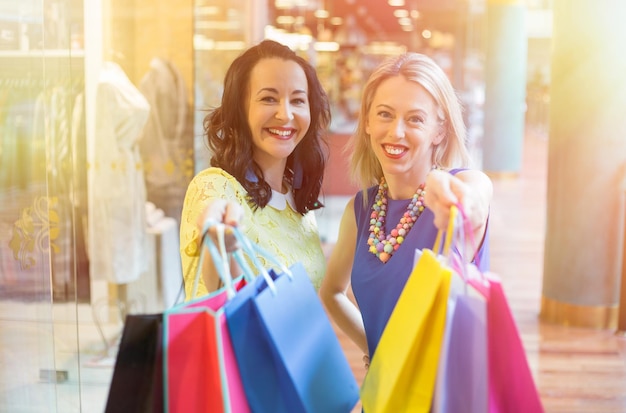 Duas amigas mostrando suas sacolas de compras