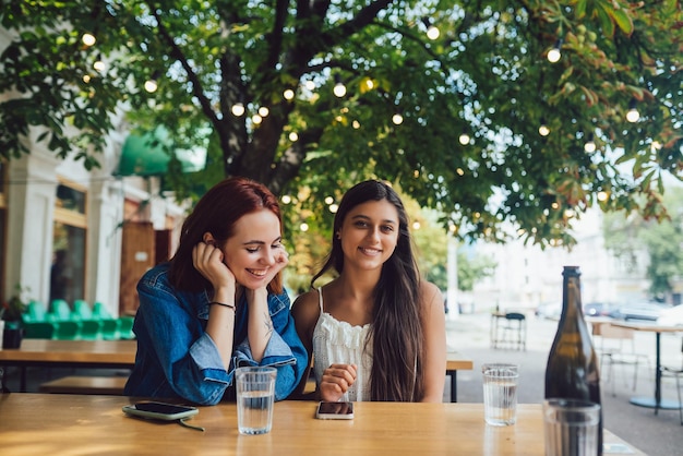 Duas amigas navegando em telefones celulares no café de rua